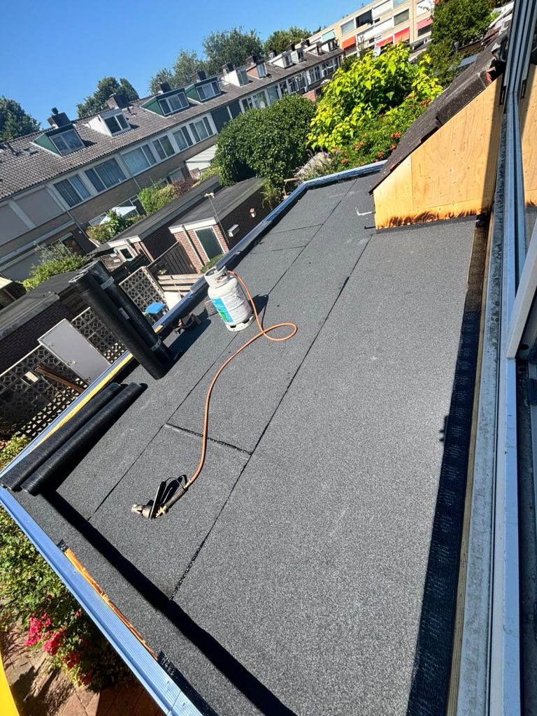 Plat dak met nieuwe gebrande bitumen toplaag en daktrim tijdens dakvernieuwing in Arnhem