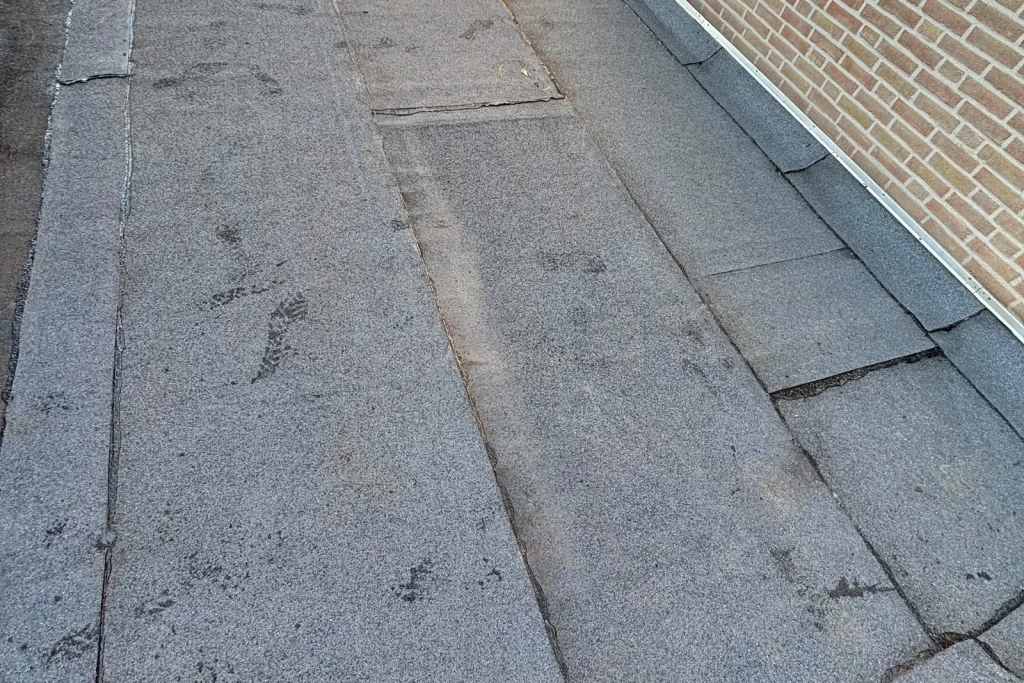 Plat dak in Eindhoven met nieuwe bitumen toplaag en strak afgewerkte opstand tegen de gevel